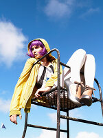 A young woman with purple hair wearing a yellow jacket and white leggings