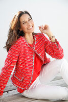 A brunette woman wearing a red jacket and white trousers