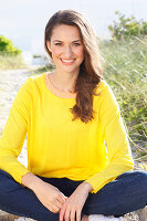 A brunette woman wearing a yellow jumper and jeans