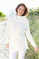 Brunette woman wearing white knit sweater and white trousers