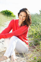 Brunette woman wearing red knit sweater and white trousers