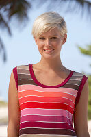 A mature blonde woman with short hair outside wearing a striped top