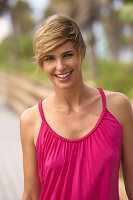 A mature blonde woman with short hair outside wearing a purple top