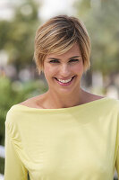 A young blonde woman with short hair outside wearing a yellow top