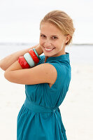 A young blonde woman on a beach wearing a blue summer dress