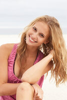 Junge Blonde Frau im rosa Top und Bikini am Strand