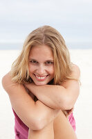 Junge Blonde Frau im rosa Top und Bikini am Strand