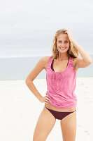 Junge blonde Frau im rosa Top und Bikini am Strand