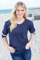 Junge blonde Frau in blauem Langarmshirt am Strand