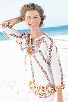 A mature woman woman by the sea wearing a printed tunic blouse