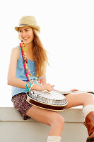 Junge blonde Frau mit blauer Weste und Rock und Gitarre