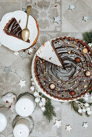 A sliced chocolate cake on a table decorated for Christmas (seen from above)