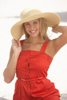 Junge blonde Frau im roten Sommerkleid und mit Sommerhut