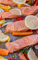 Lemon salmon with peppers, carrots, olive oil and rosemary on baking paper