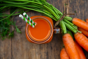 Karottensmoothie mit Strohhalmen in Glas-Henkelbecher (Aufsicht)