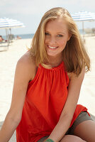 A blonde woman on a beach wearing an orange top