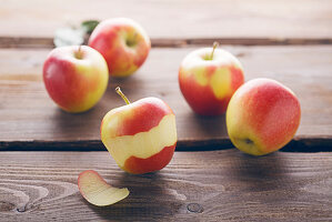 Apples on a wooden background, one partially peeled