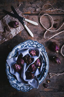 Small violet artichokes in a ceramic bowl on a wooden surface