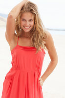 A young blonde woman on a beach wearing a red summer dress