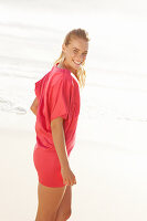 Blonde Frau in rotem Kleid am Strand