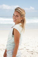 A blonde woman on the beach wearing a light t-shirt