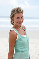 A blonde woman on a beach wearing a turquoise top