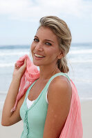 A blonde woman on a beach with a scarf and a turquoise top