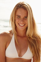 A blonde woman on a beach wearing a white bikini