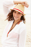 A brunette woman wearing a hat, a red bikini top and a white blouse
