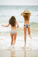 Two women wearing bikinis and summer hat on the beach