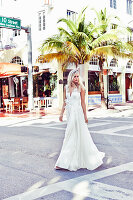 Junge blonde Frau in einem weißen Brautkleid auf der Straße