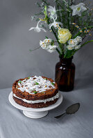 Carrot cake with coconut chips, cream cheese and quark cream and edible flowers for an Easter breakfast