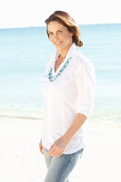 Brünette Frau in weißem Hemd am Strand