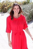 A brunette woman outside wearing a red dress