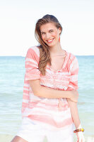 A young woman by the sea wearing a striped blouse and shorts