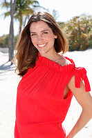 A brunette woman outside wearing a red top