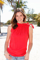 A brunette woman outside wearing a red top