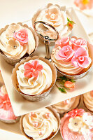Festliche Cupcakes verziert mit Cremetopping und Zuckerblüten