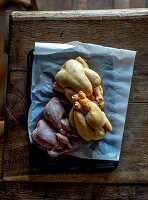 Raw chicken and quails on parchment paper