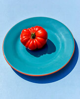 Rote Tomate auf blauem Teller