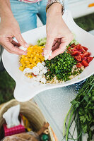 Ingredients for a colourful bulgur salad being placed in a bowl