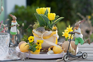Easter table decoration with tulip and horn violets, Easter eggs and Easter bunnies