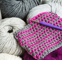 A crocheted gauge in two colours with a crochet hook
