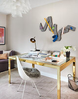 Brass desk with glass top and white chair in study