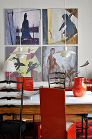 Wooden table with marble top, black and red chairs and artwork on wall of dining area