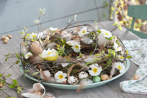 Osterkranz aus Zweigen, dekoriert mit Primelblüten, Eierschalen, Federn und Steckzwiebeln