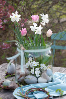 Daffodils 'Toto', tulips and horned violets without soil in the glass, Easter eggs and willow wreaths as decorations