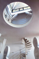 Spiral staircase and artwork in loft apartment with circular aperture below skylight