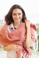 Junge brünette Frau in heller Hemdbluse mit lachsfarbener Stola aus Wolle