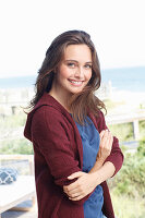 A young brunette woman wearing a blue t-shirt and a wine red cardigan